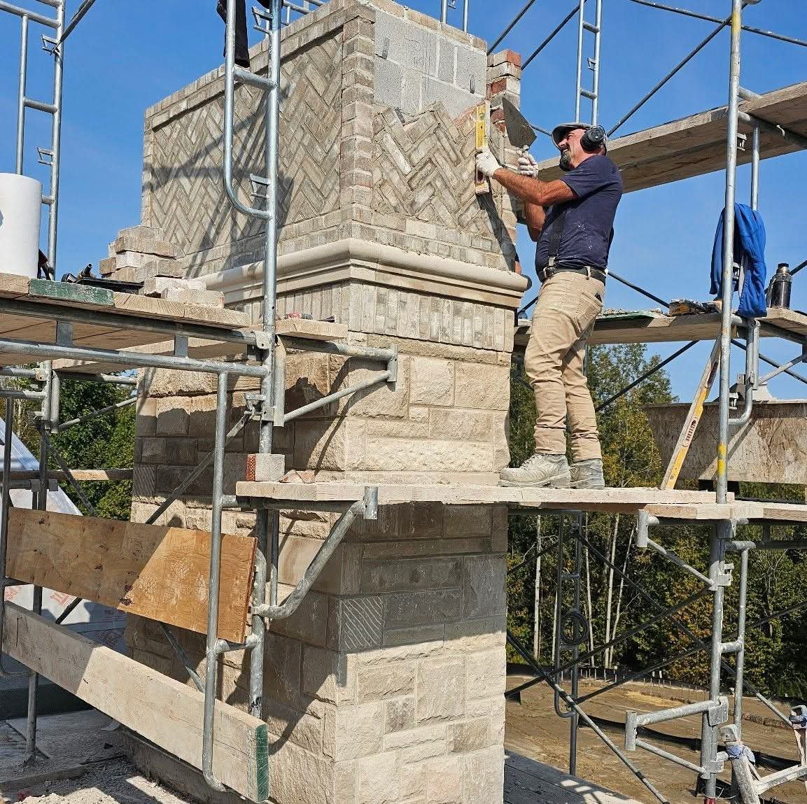 Phil Wright rebuilding a heritage stone chimney on scaffold