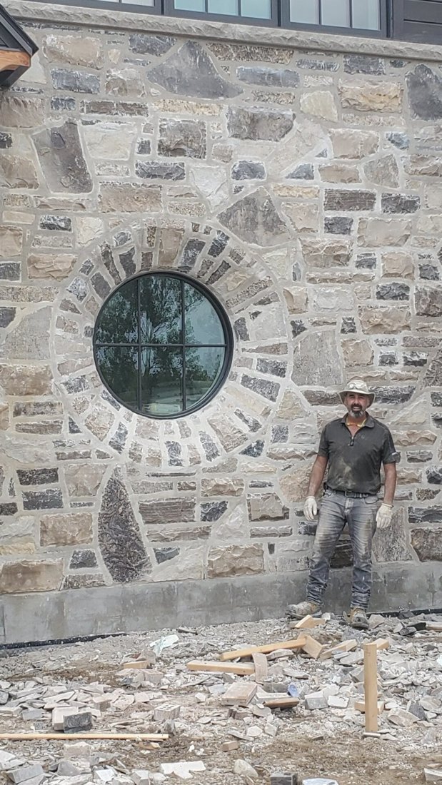 Phil Wright beside a stone oculus window he built